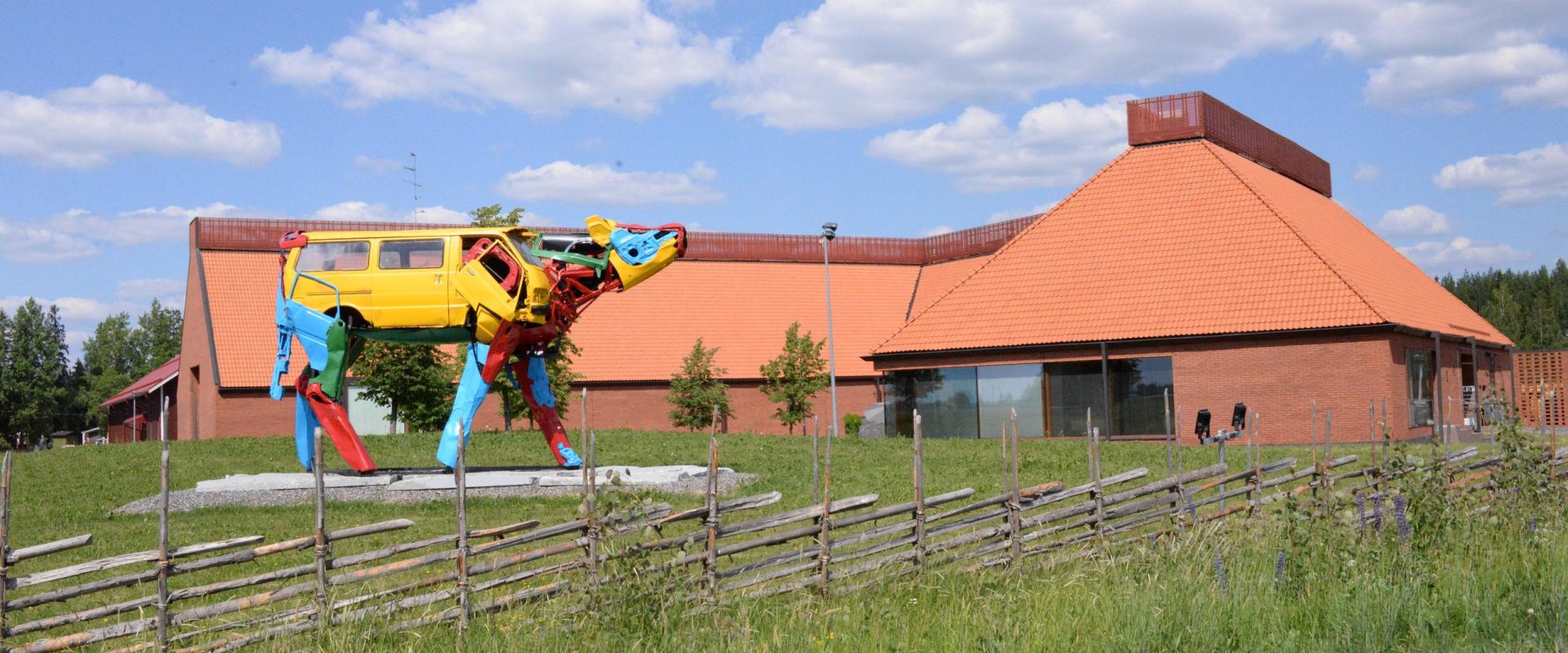 Museorakennus ja värikäs lehmäveistos kesällä