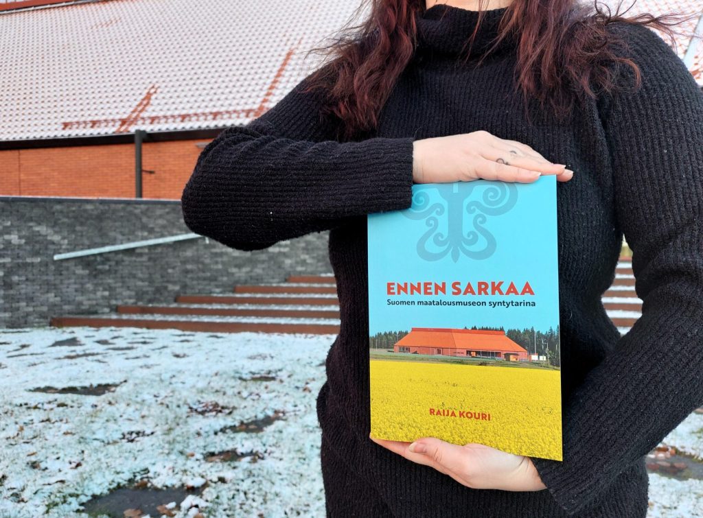 Henkilö pitämässä kädessään Ennen Sarkaa -historiikkikirjaa